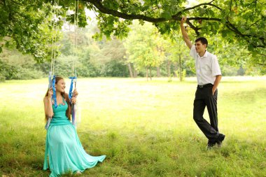 Kız onun yanında duran adam bir salıncak üzerinde sürme