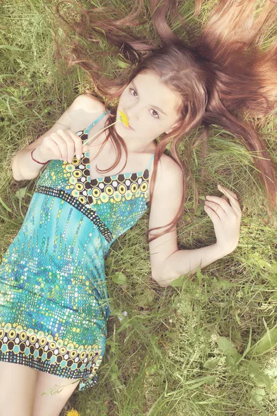 夢のような女性は草やにおいを嗅ぐタンポポに横たわっています — ストック写真
