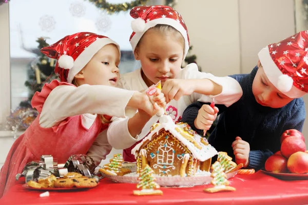 Three Kids Caps Decorated Gingerbread House — Stock Photo, Image
