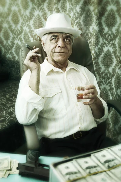 Old happy man pensively smoking a cigar