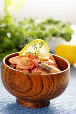 Limonlu haşlanmış karides ve ahşap bir kasede dereotu.