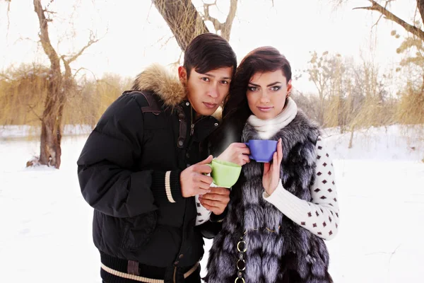 Young couple with a hot drink in winter outdoors