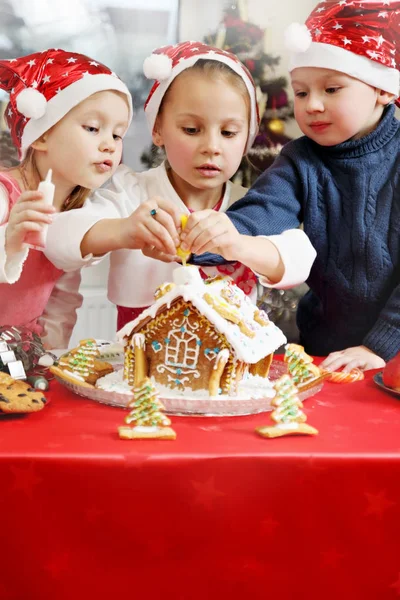 Three Kids Caps Decorated Gingerbread House — Stock Photo, Image