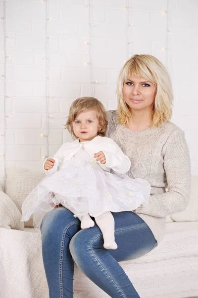 白いベッドの上に座っている彼女の娘を抱いて母 — ストック写真