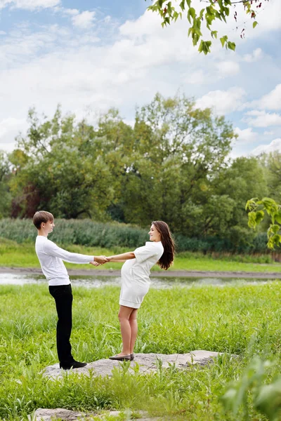 若いカップルが手を繋いでいる草原を歩く — ストック写真
