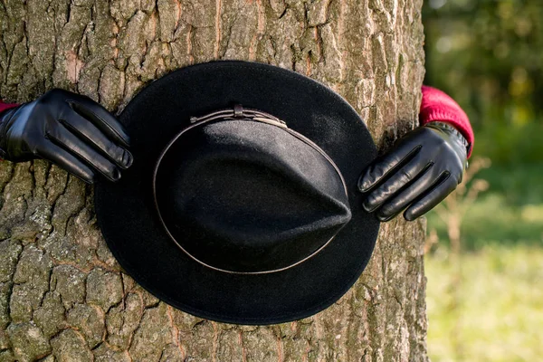 Femme en gants tient un chapeau noir — Photo