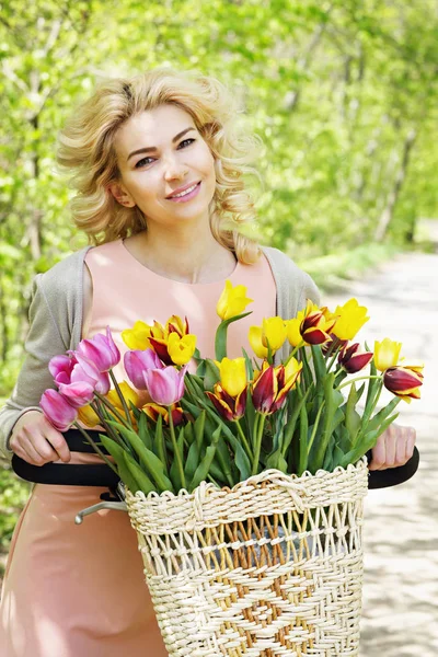 Krásná žena na kole s kyticí tulipánů — Stock fotografie