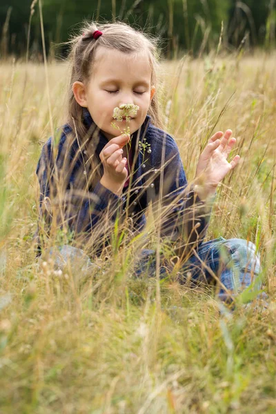 Menina cheira uma flor — Fotografia de Stock