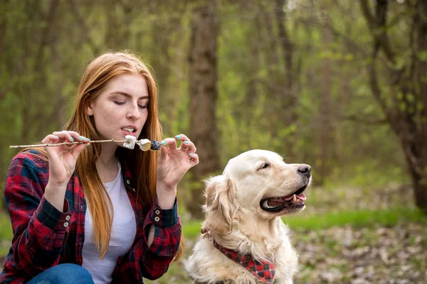 Red-haired woman bites roasted marshmallows — Stock Photo, Image