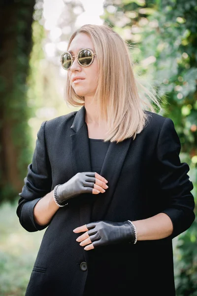 Rubia con chaqueta negra y guantes con cadena —  Fotos de Stock