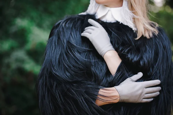 Vrouw in een zwarte jas en grijze handschoenen — Stockfoto
