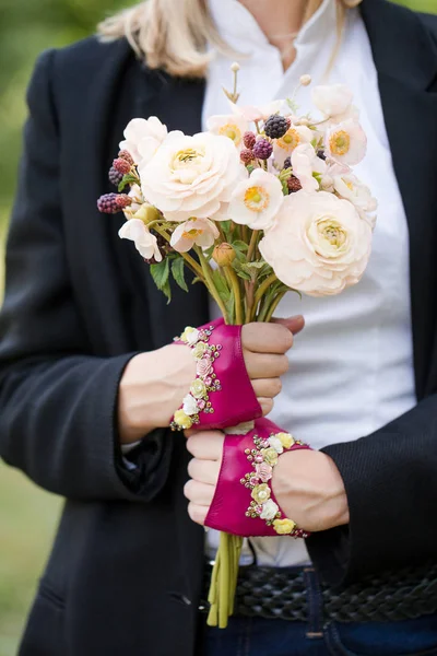 Mãos em luvas rosa curtas com um buquê — Fotografia de Stock