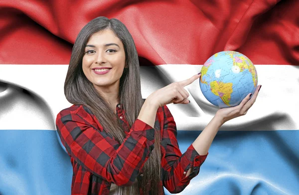Young female Tourist holding Earth Globe against flag of Luxemborug