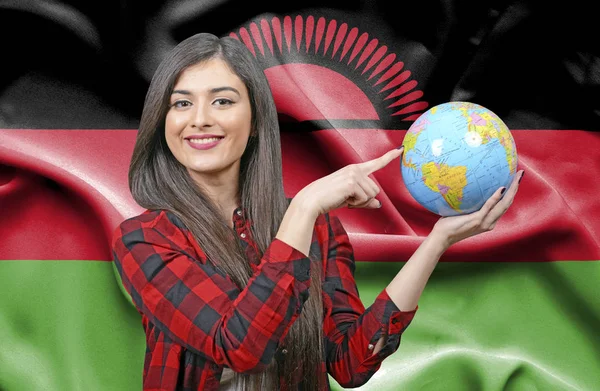 Young female Tourist holding Earth Globe against flag of Malawi
