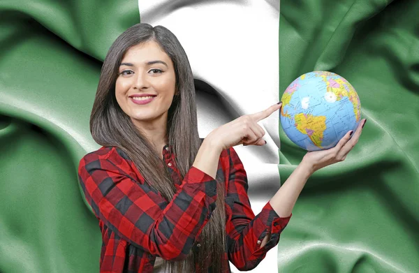 ナイジェリアの旗に対して地球を保持若い女性観光客 — ストック写真