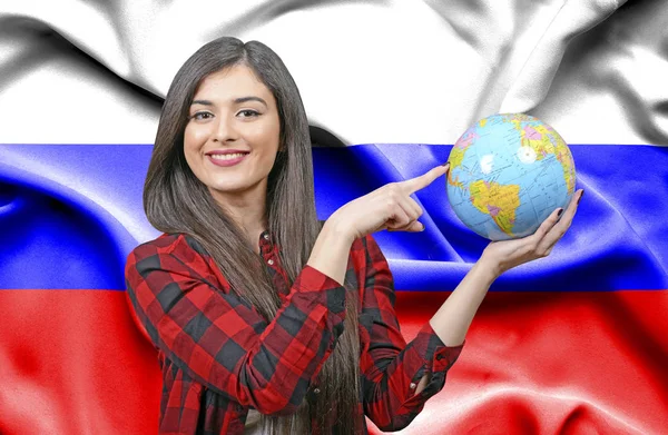 Young female Tourist holding Earth Globe against flag of Russia