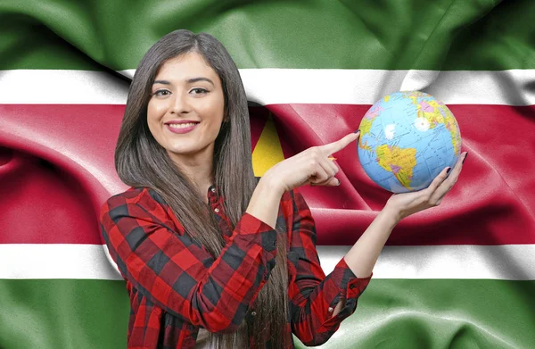 スリナムの国旗に対して地球を保持若い女性観光客 — ストック写真