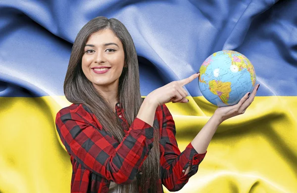 年轻女性游客拿着地球地球反对乌克兰国旗 — 图库照片
