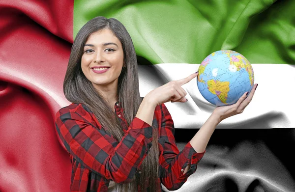 Young female Tourist holding Earth Globe against flag of United Arab Emirates