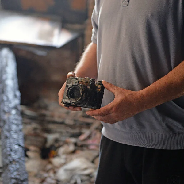 男人拿着被烧毁的相机在被烧毁的房子里 — 图库照片