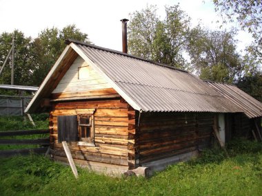 Güneşli bir günde çim çevrili bir köyde ahşap bir Rus Hamam