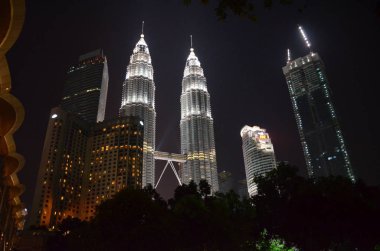 Kuala Lumpur, Malezya - 22 Nisan 2017: Gece görünümü aşağıdan ışıklı Petronas İkiz Kuleleri ve komşu binaların Kuala Lumpur, Malezya