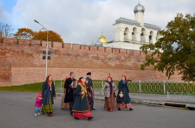 Velikiy Novgorod, Rusya Federasyonu - 4 Ekim 2014: Erkekler ve kadınlar, geleneksel kostümler giymiş Kremlin yolda çan kulesi arka plan üzerinde yürümek.