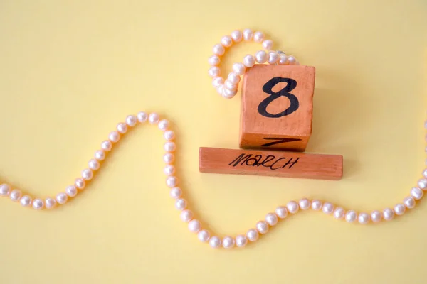 3月8日の木製永久カレンダーと黄色の背景に天然の海ピンクの真珠から作られたビーズとブレスレット 母の日 国際女性デーの概念 — ストック写真