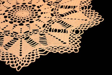 İzole bir parçası bej dantel siyah bir arka planda bir geometrik desen ile tığ işi. Yuvarlak dekoratif pamuk doily. Yan görünüm