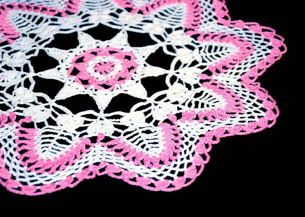 黒の背景に葉のパターンを持つ独立したかぎ針編みの白とピンクのドイリーの一部 丸い装飾的な綿のドイリー 側面図 — ストック写真