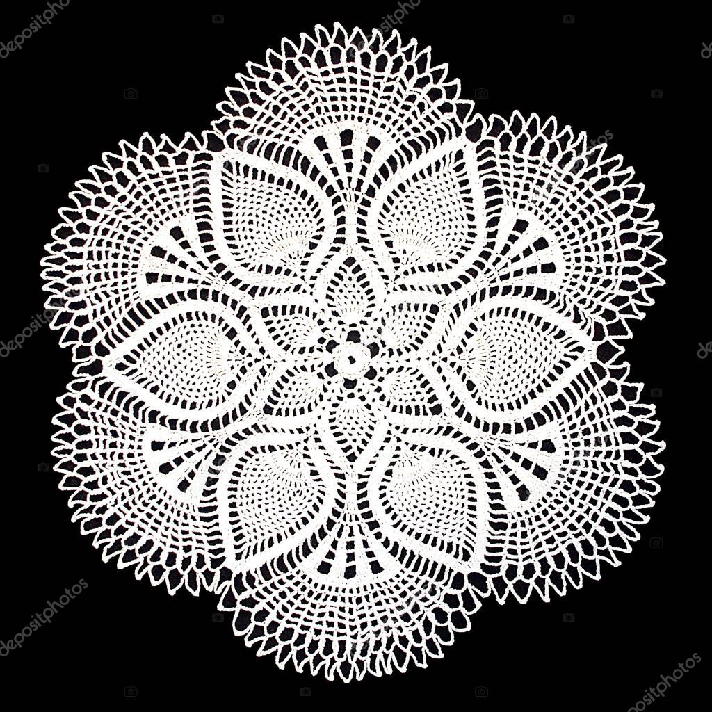 Isolated crocheted white doily with a pattern of cones on a black background. Round decorative cotton doily. Top view