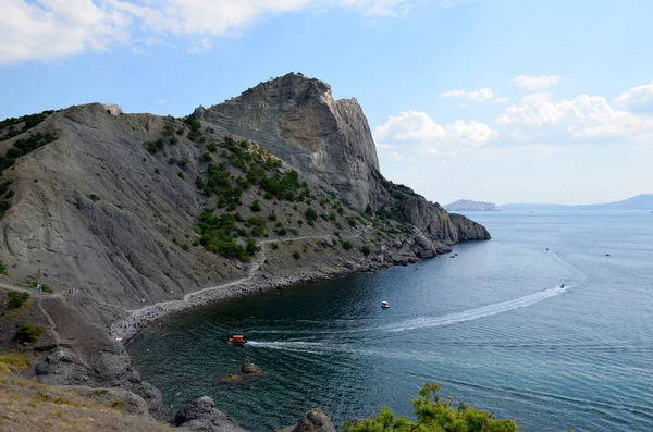 在阳光明媚的夏日 克里米亚诺维锡村附近的黑海蓝湾和戈利岑小径的俯瞰 人们在岩石沙滩上放松一下 然后洗澡 摩托艇在水面上留下痕迹 — 图库照片