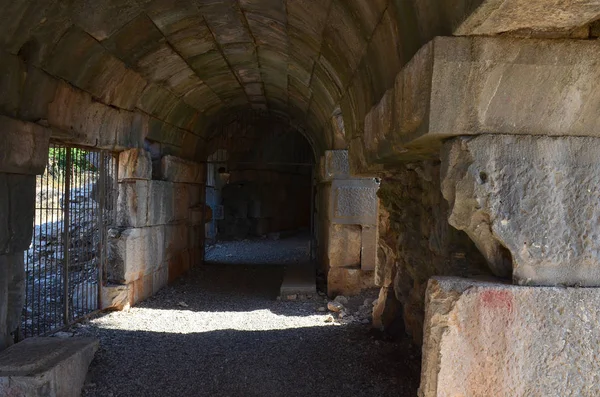 Caminho através de um túnel arqueado curvo escuro em velhas ruínas de pedra — Fotografia de Stock
