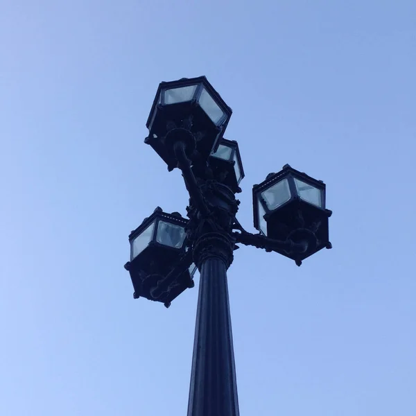 Old cast-iron street lantern with four lamps behind glass agains — Stock Photo, Image