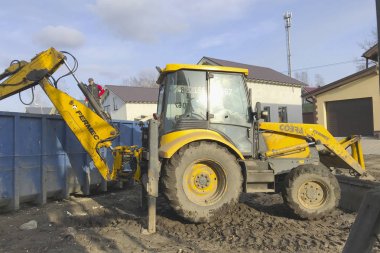 Büyük sarı traktör inşaat çöplerini bir konteynere yükler
