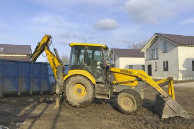 Büyük sarı traktör inşaat çöplerini bir konteynere yükler