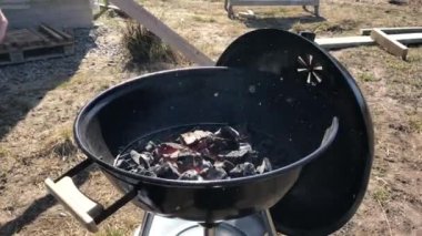 Izgara ızgaraüzerinde kömür ve odun yakmak. Büyük yuvarlak açık ızgara barbekü için kömür hazırlanması. Rahatlama ve yemekten zevk kavramı
