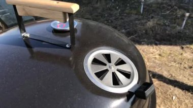 Termometre ile büyük kapalı yuvarlak ızgara kapatın. Barbekü pişirme süreci. Rahatlama ve yemekten zevk kavramı. Duman deliklerden çıkıyor.