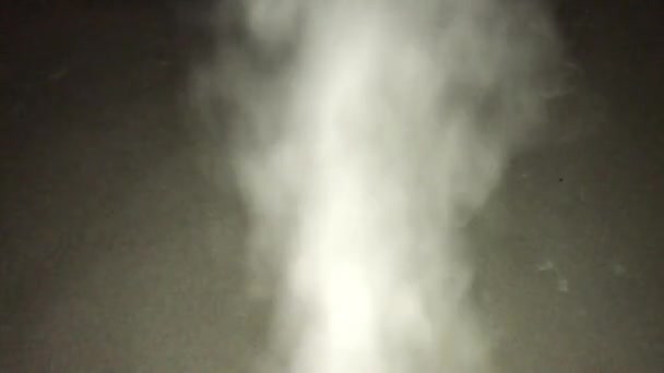 Mouvement de la caméra à travers un jet de vapeur blanche et retour. Un jet de vapeur dans le rétroéclairage sur un fond sombre 