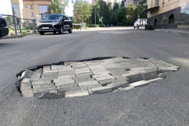 Yol onarım konsepti. Asfaltta tuğla bulunan bir çukurun kapatılması