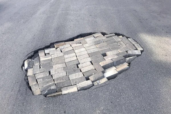 도로 수리 개념. 아스팔트 도로에 벽돌구덩이 스톡 사진