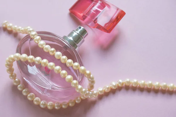 Otwarta butelka perfum i sznur pereł na różowym z miejscem — Zdjęcie stockowe