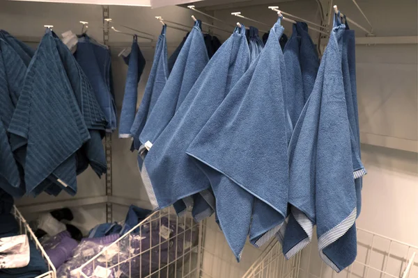Molti asciugamani di spugna blu e viola pendono sui ganci del negozio. Co — Foto Stock