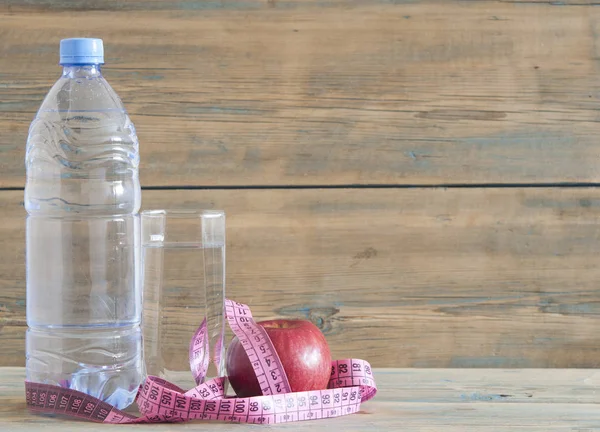 Plastic water bottle and water glass on wooden table.Health diet and fitness lifestyle concept