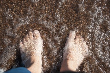 Bir adamın çıplak ayak closeup yavaşça altlarında köpük dalga'nın kenar ile sahilde, ıslak, stand