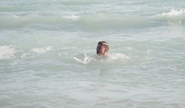 Genç çocuk sahilde dalgalar ile eğleniyor