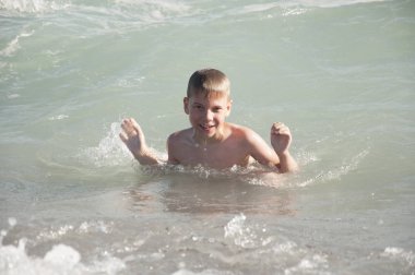 Genç çocuk sahilde dalgalar ile eğleniyor