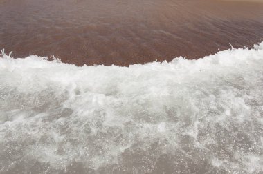 Sandy beach ile temizleyin yumuşak dalga beyaz köpük köpük ile güneşli günde