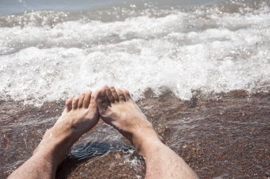 Bir adamın çıplak ayak closeup yavaşça altlarında köpük dalga'nın kenar ile sahilde, ıslak, stand