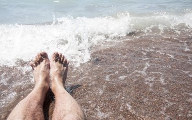 Bir adamın çıplak ayak closeup yavaşça altlarında köpük dalga'nın kenar ile sahilde, ıslak, stand